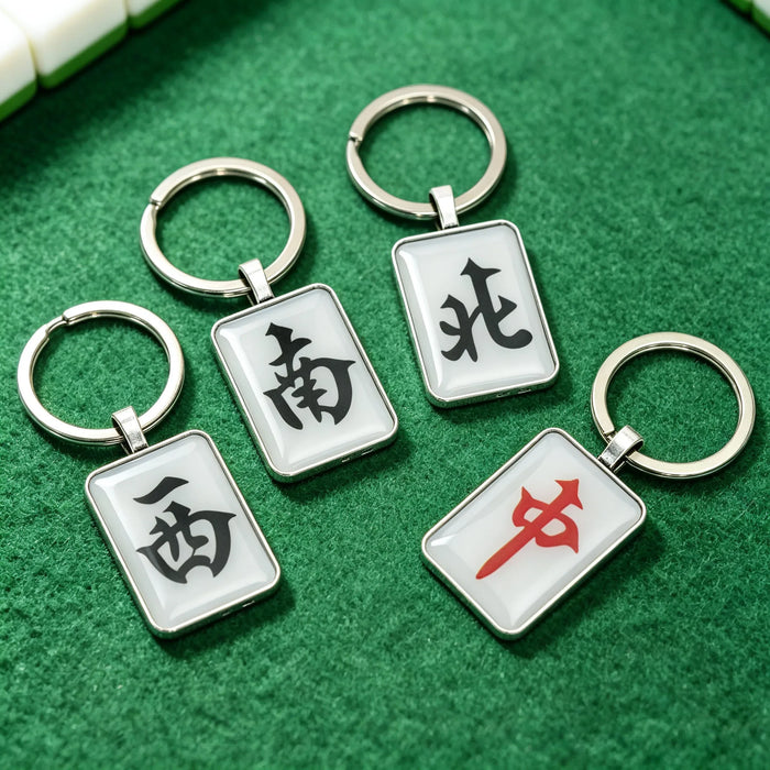Mahjong tile keychains with wind and dragon tiles on a green mat